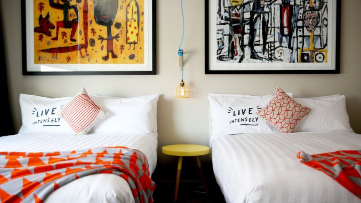 Two single beds in a hotel room with paintings above each bed